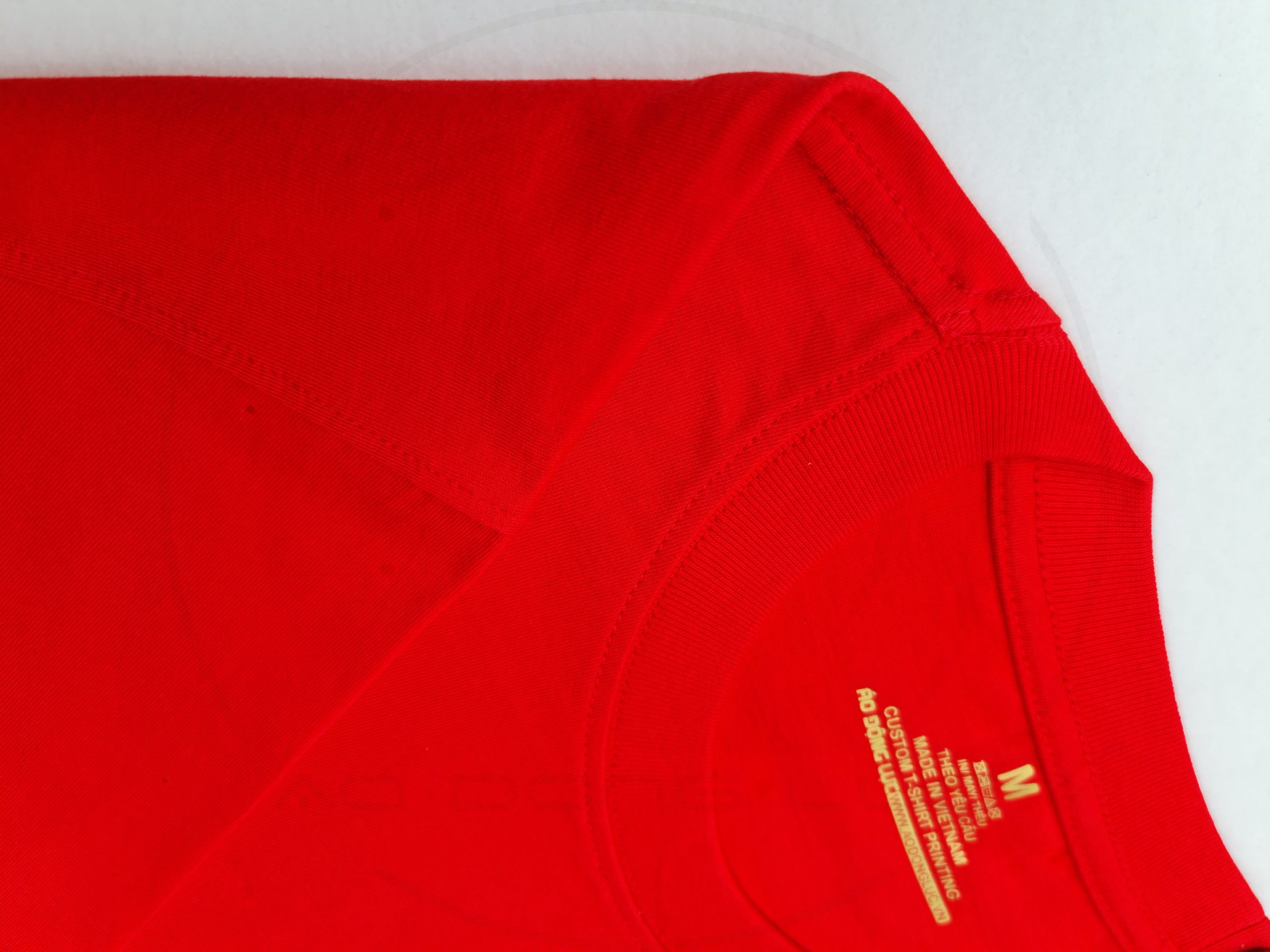 Chi tiết đường may và cổ áo áo thun cổ tròn tay lỡ oversize màu đỏ tươi