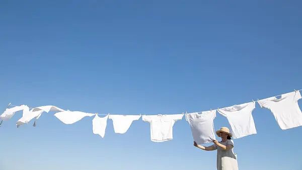 Người phụ nữ đang treo quần áo lên dây phơi dưới bầu trời xanh